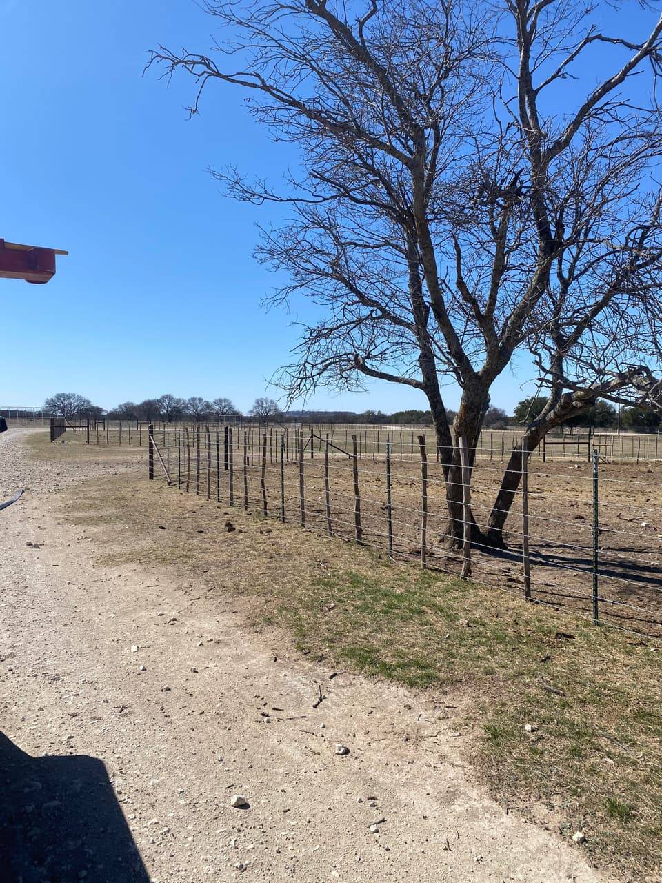 Ranch & Farm Fencing example — Woven wire fence secured to steel pipe posts along a ranch road, Central Texas ranch