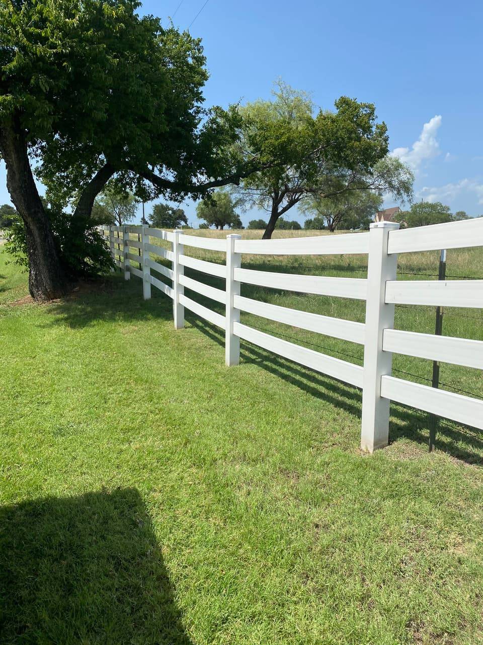 Ranch & Farm Fencing example — White vinyl 4-rail fence along pasture frontage, Central Texas ranch entrance